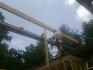 Carpenter setting a ridge beam over a new addition frame — Ice Dam Removal by Roofing Brothers in Hughes Springs