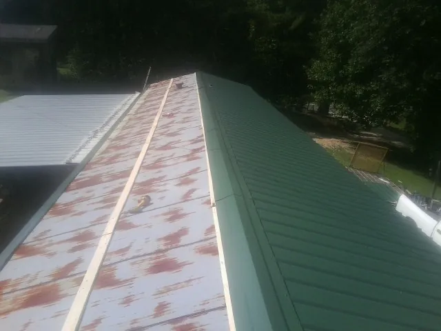 Old rusted panels beside newly installed green metal roofing — Wind Damage Roof Repair by Roofing Brothers in Hughes Springs