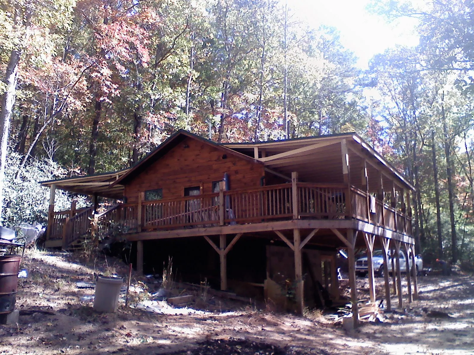 Log cabin with a wraparound porch and metal roof in the fall in Hughes Springs