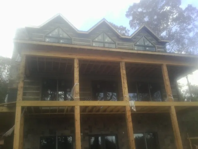 Dormers and porch framing on a large log home under construction — Roof Coating work by our crew in Hughes Springs