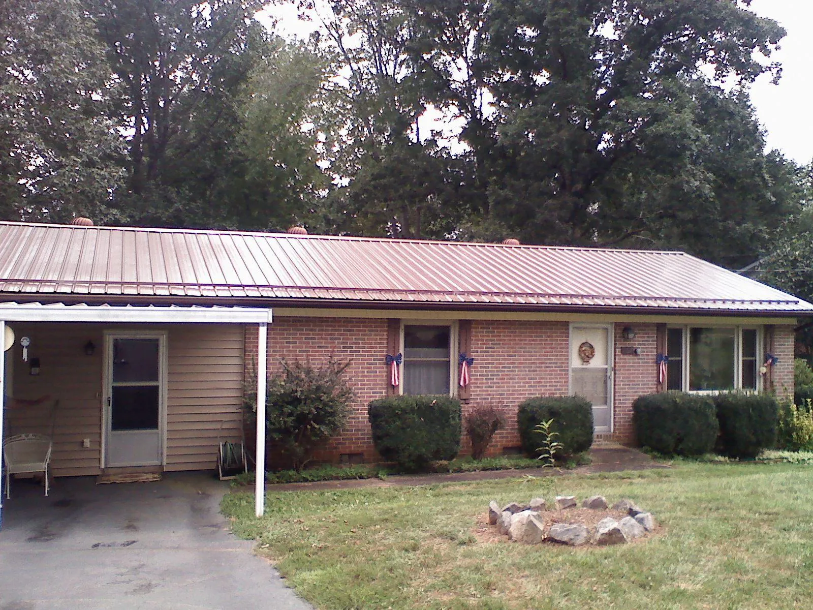 Bronze metal roof and carport on a brick ranch home — Roof Repair work by our crew in Hughes Springs