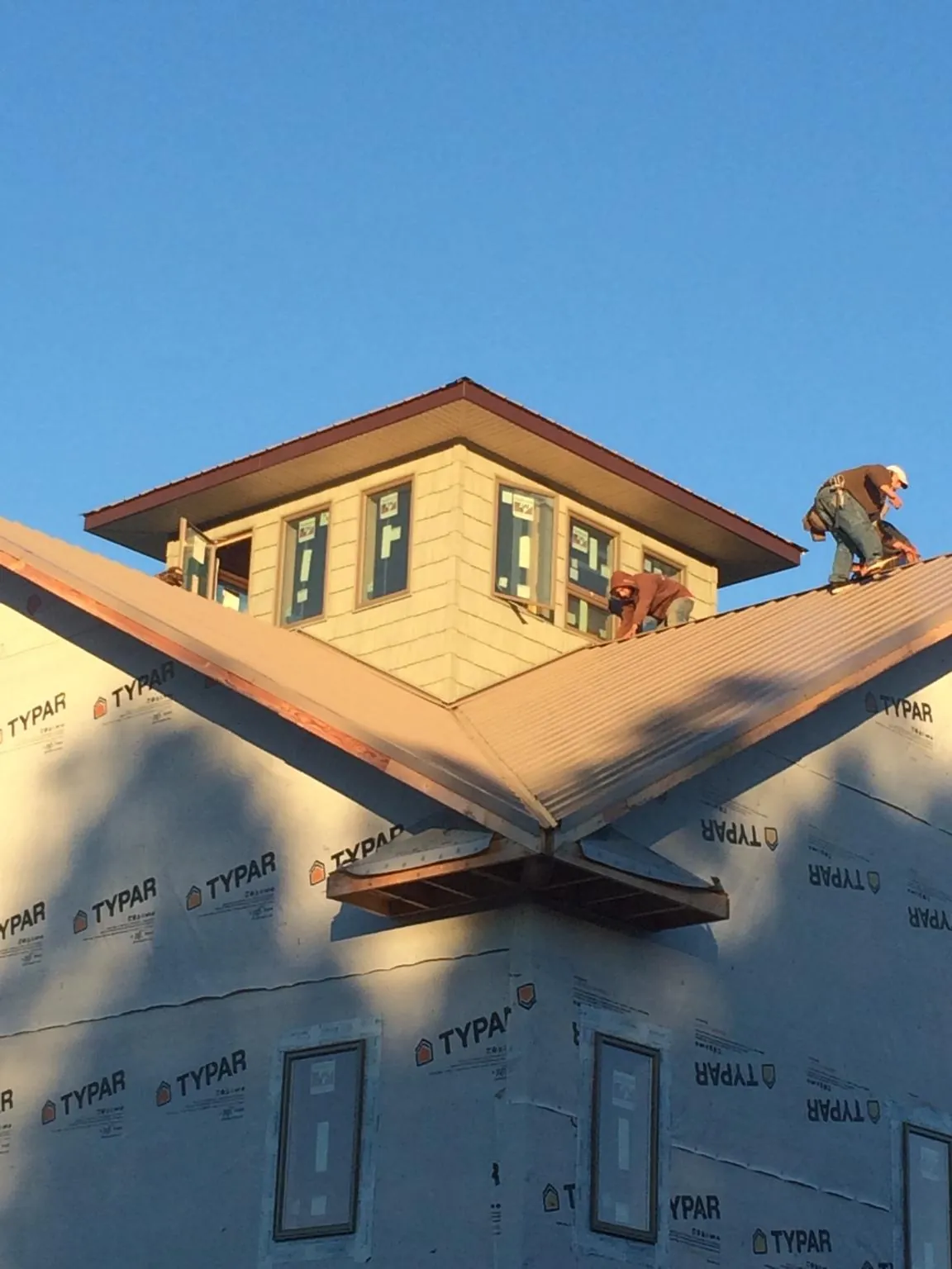 Roofers working around a rooftop cupola on a new metal roof at sunset — Roof Waterproofing in Hughes Springs by Roofing Brothers
